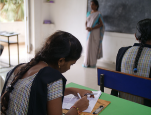 An Indian girl writes on a desk in classroom as she recovers from trafficking